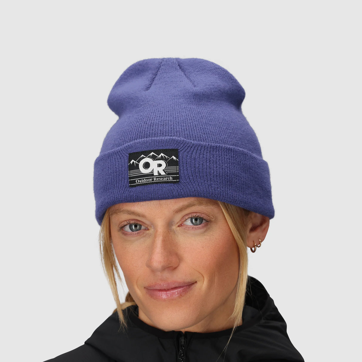 Person wearing a Outdoor Research Juneau Beanie in Galactic with a logo on a gray background