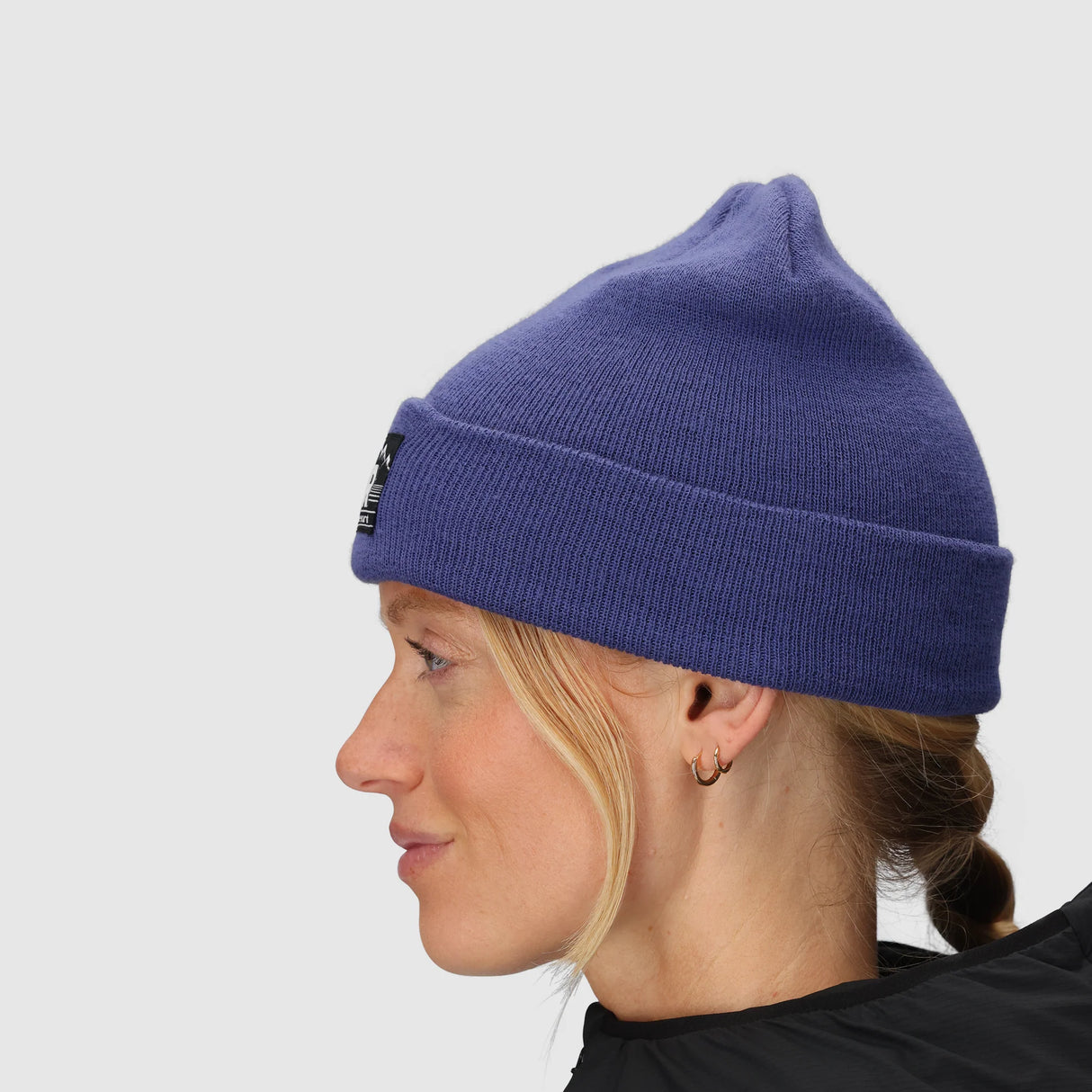 Person wearing a Outdoor Research Juneau Beanie in Galactic with a small logo on a light gray background