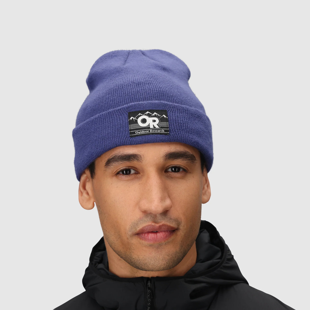 Person wearing a Outdoor Research Juneau Beanie in Galactic with a logo on a gray background