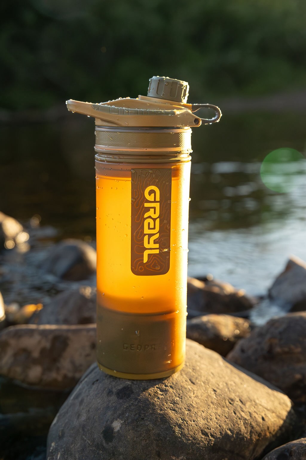 Grayl GeoPress Water Purifier Bottle on a river rock in Coyote Brown.