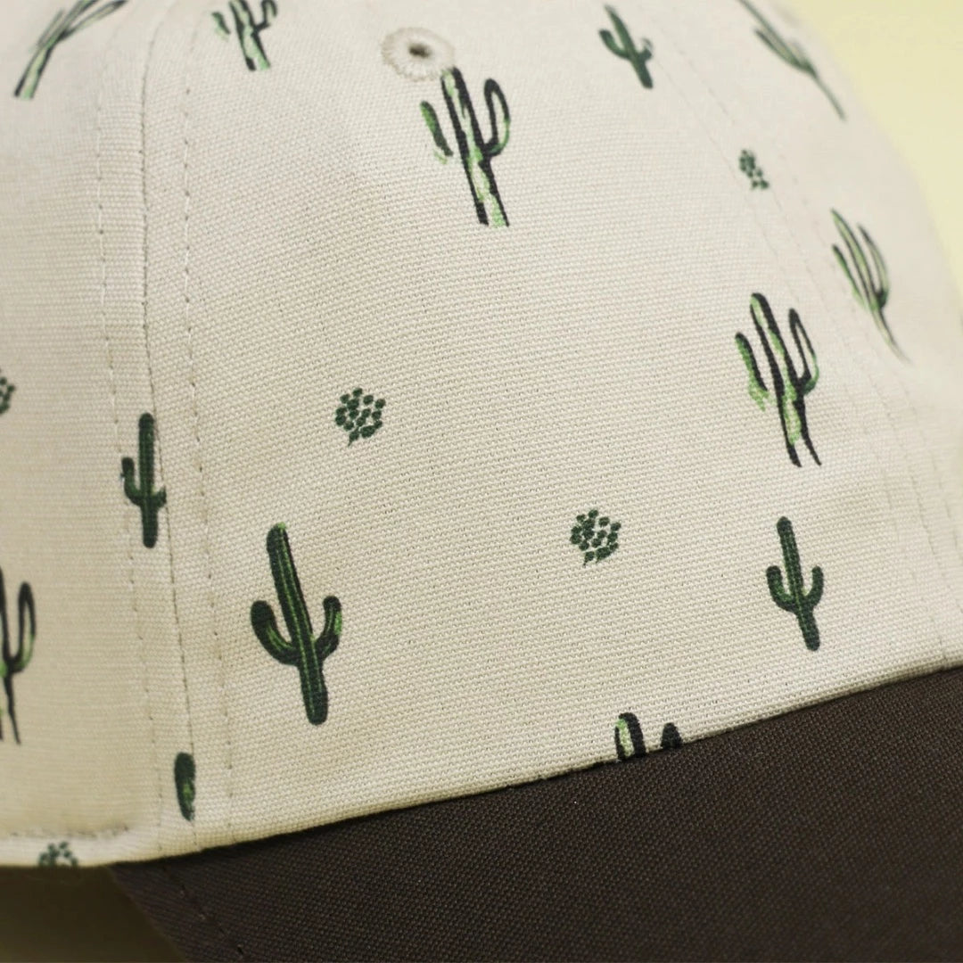 Closeup of the neutral colored hat printed with small, green cacti made from sustainable materials, showcasing eco-friendly fashion.