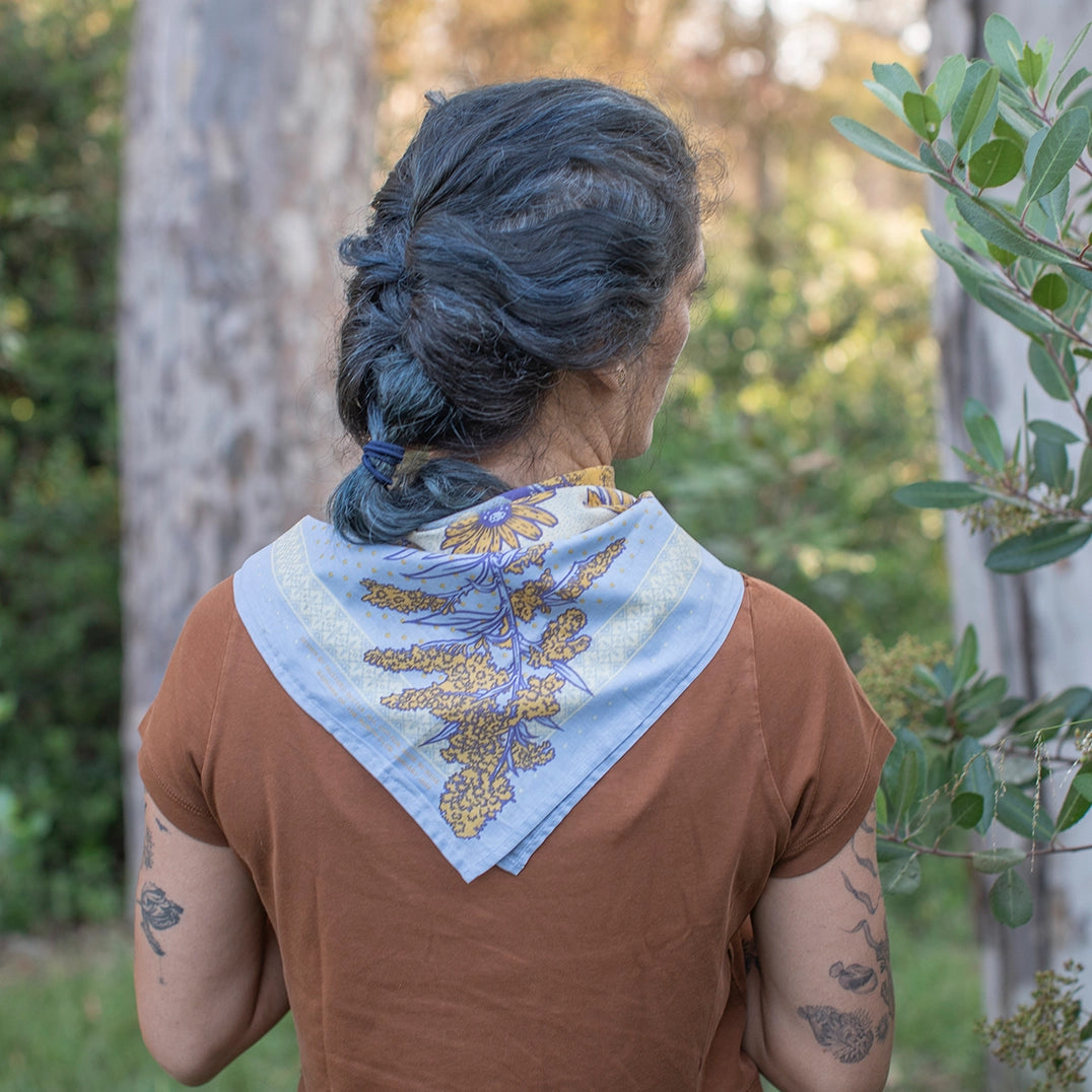 Mustard Beetle Bandana of the Month Club bandana worn by a woman outdoors.