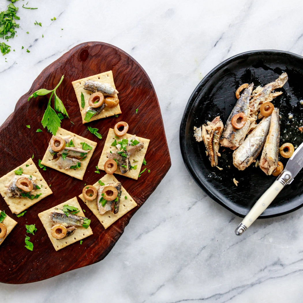 Plated Lemon Olive Spanish White Anchovies with crackers and garnishes on a marble surface