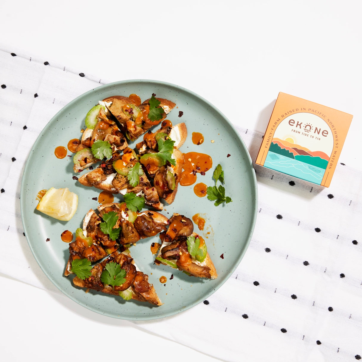 Ekone Habanero Smoked Oysters tinned seafood packaging and contents with food on a neutral background.