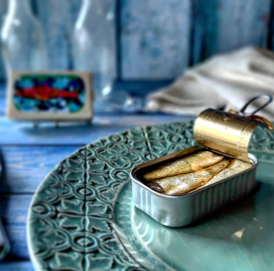 Open can of Jose Gourmet Sardines in Extra Virgin Olive Oil on a decorative plate with a blurred background