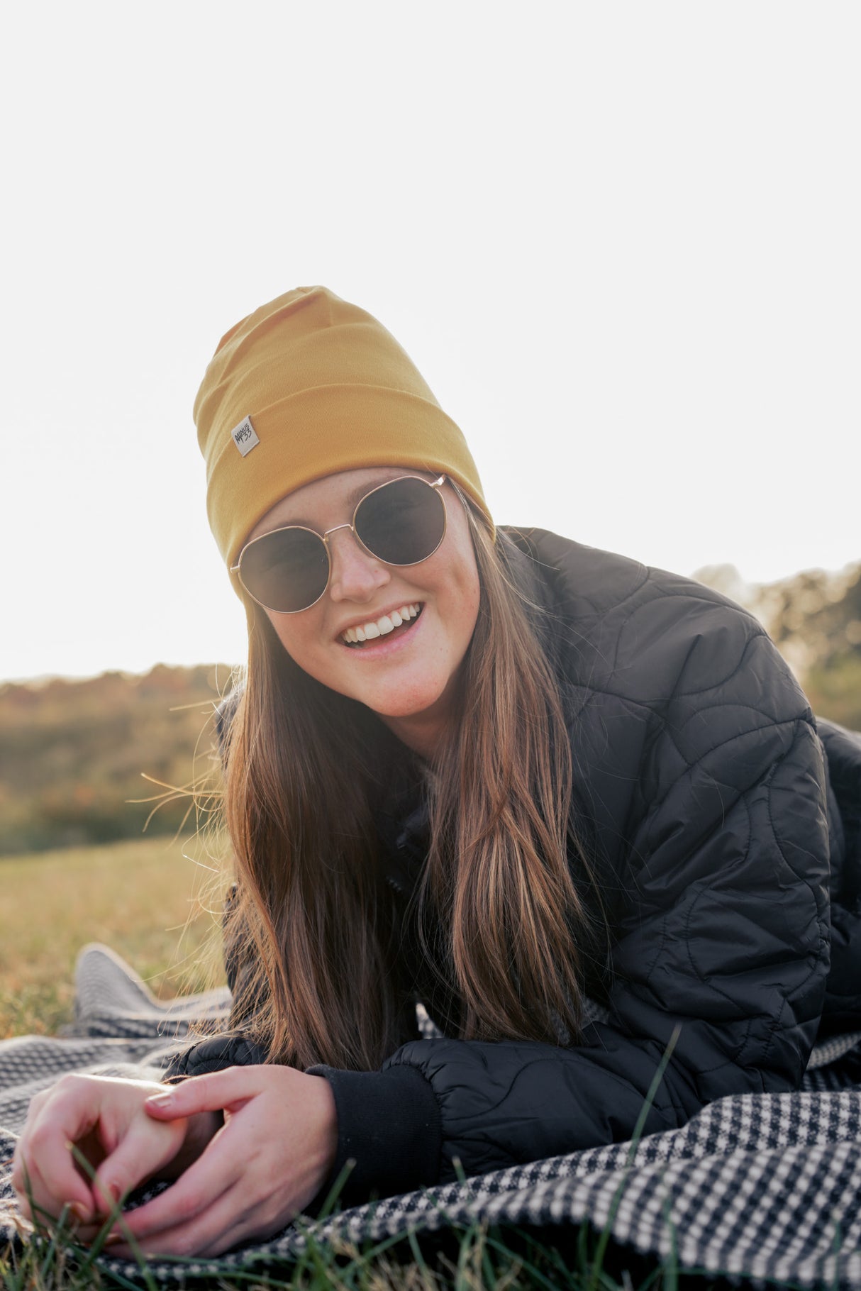 Minus33 Ridge Cuff Merino Wool Beanie in Gold being worn by a woman outdoors.