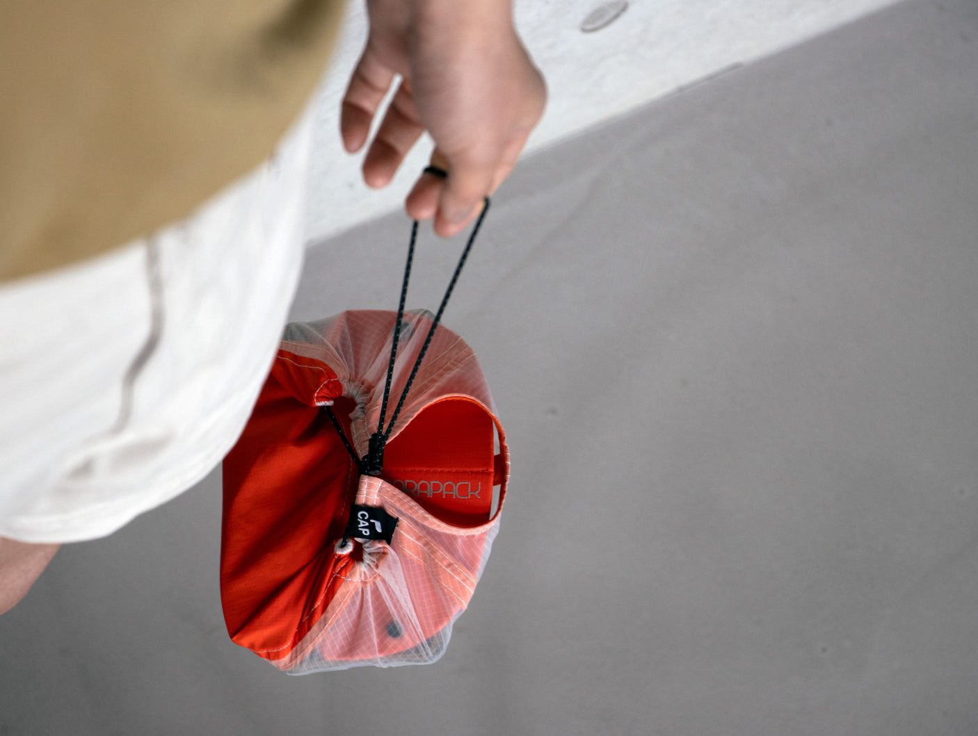 Parapack P-Cap Lite lightweight hat in Redrock packed down and being carried by its cord.