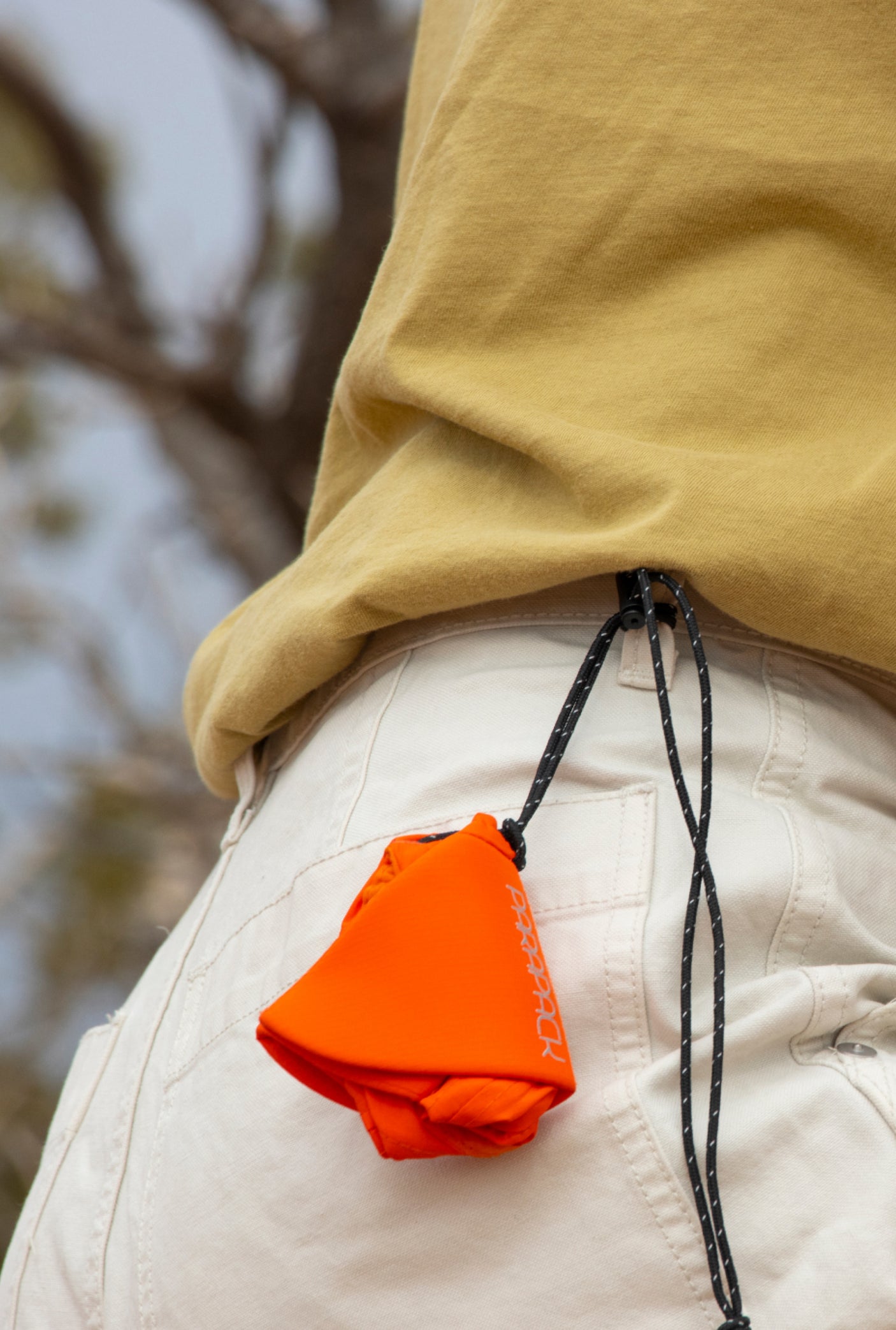 Parapack P-Cap Lite lightweight hat in Redrock packed down and worn on a belt loop.