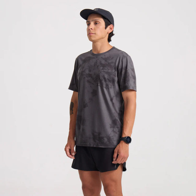 Man wearing a Roark Mathis Active Tie Dye Pocket Short Sleeve Tee in Gray and black shorts on a white background