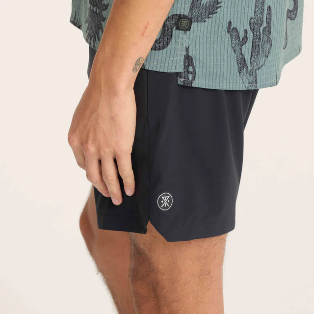 Person wearing Roark Serrano 7" Active Stretch Shorts in Black with a brand logo on a plain background