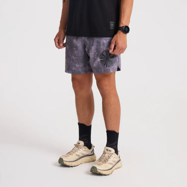 Person wearing black t-shirt, Roark Serrano 7" Active Stretch Shorts in Shark, and beige sneakers on a white background