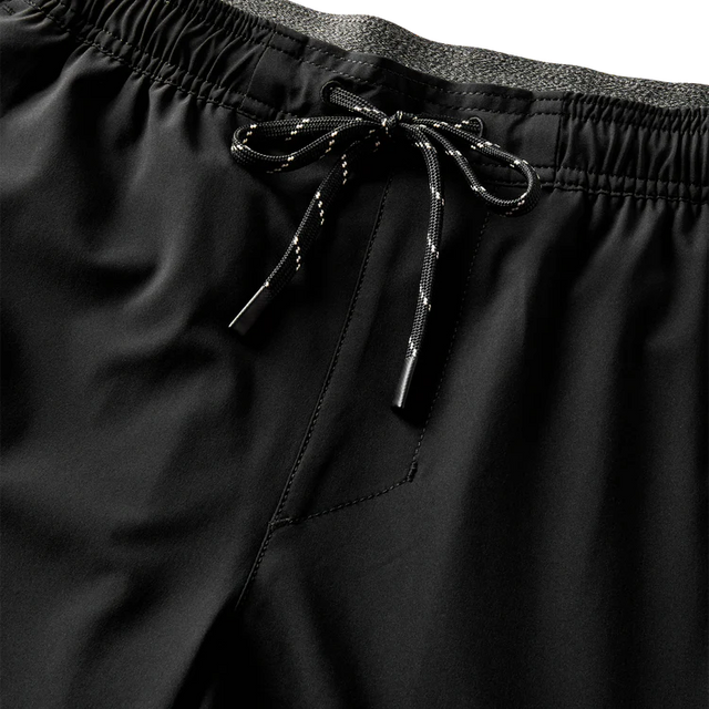 Close-up of Roark Serrano 7" Active Stretch Shorts in Black with drawstring on a dark background