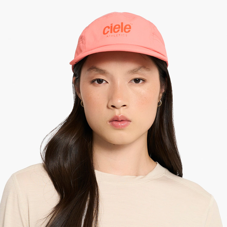 Person wearing a Ciele Athletics GOCap Classic - Athletics Blossom Coral running cap with 'ciele Athletics' logo on a white background