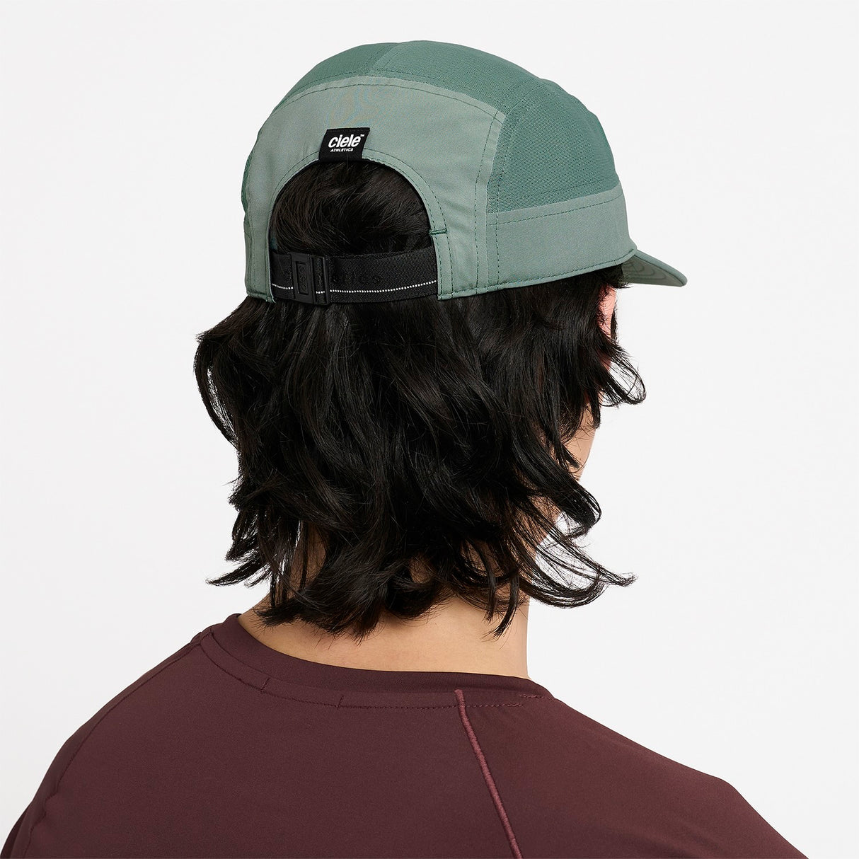 Person wearing a Ciele Athletics GOCap Comp Century Silver Pine green running cap on a white background