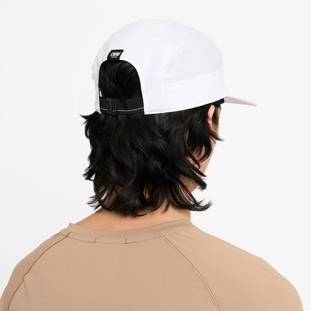 Person wearing a Ciele Athletics GOCap Comp Century Trooper white running cap on a plain background