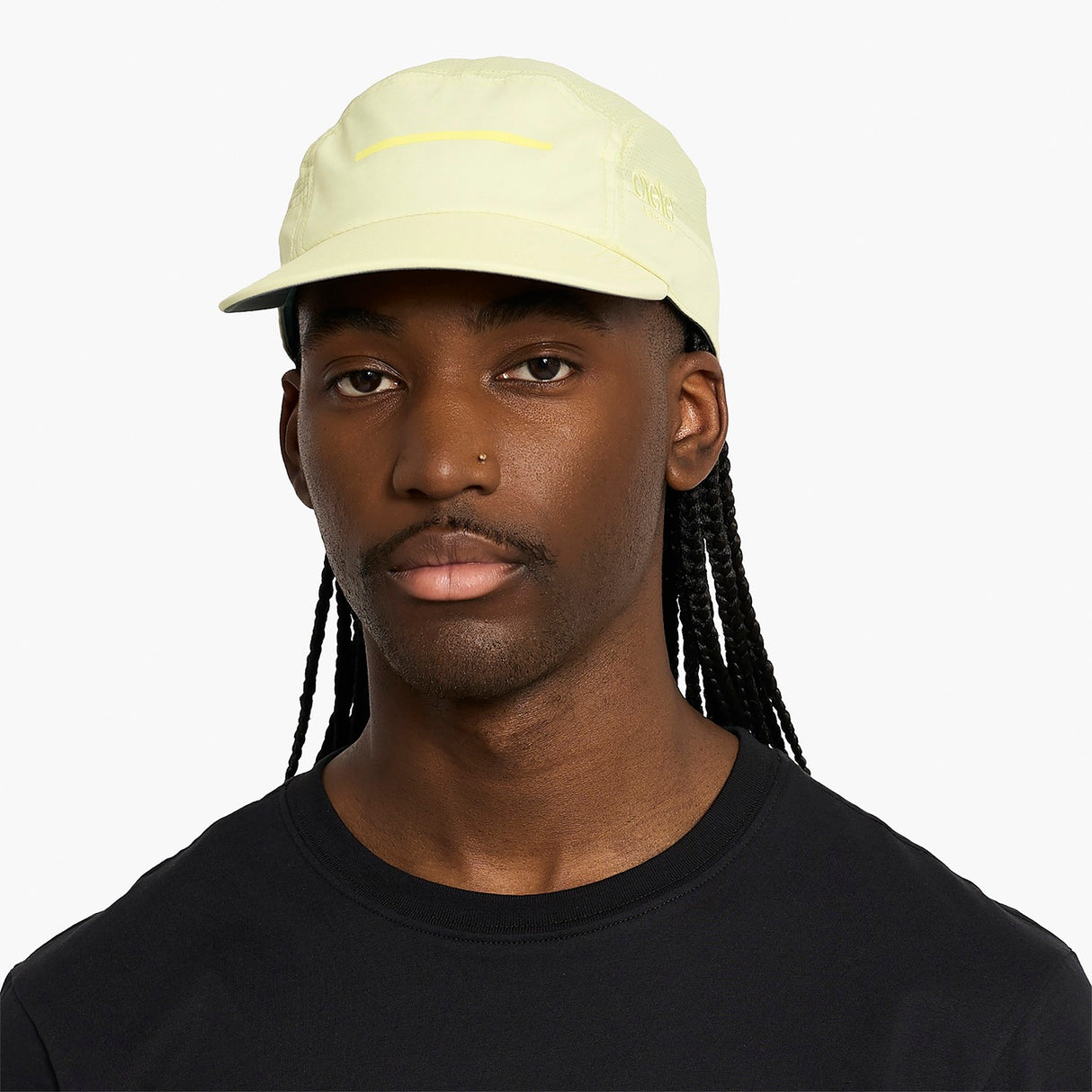 Person wearing a ciele athletics GOCap Comp - Bars Glade light yellow running cap on a white background