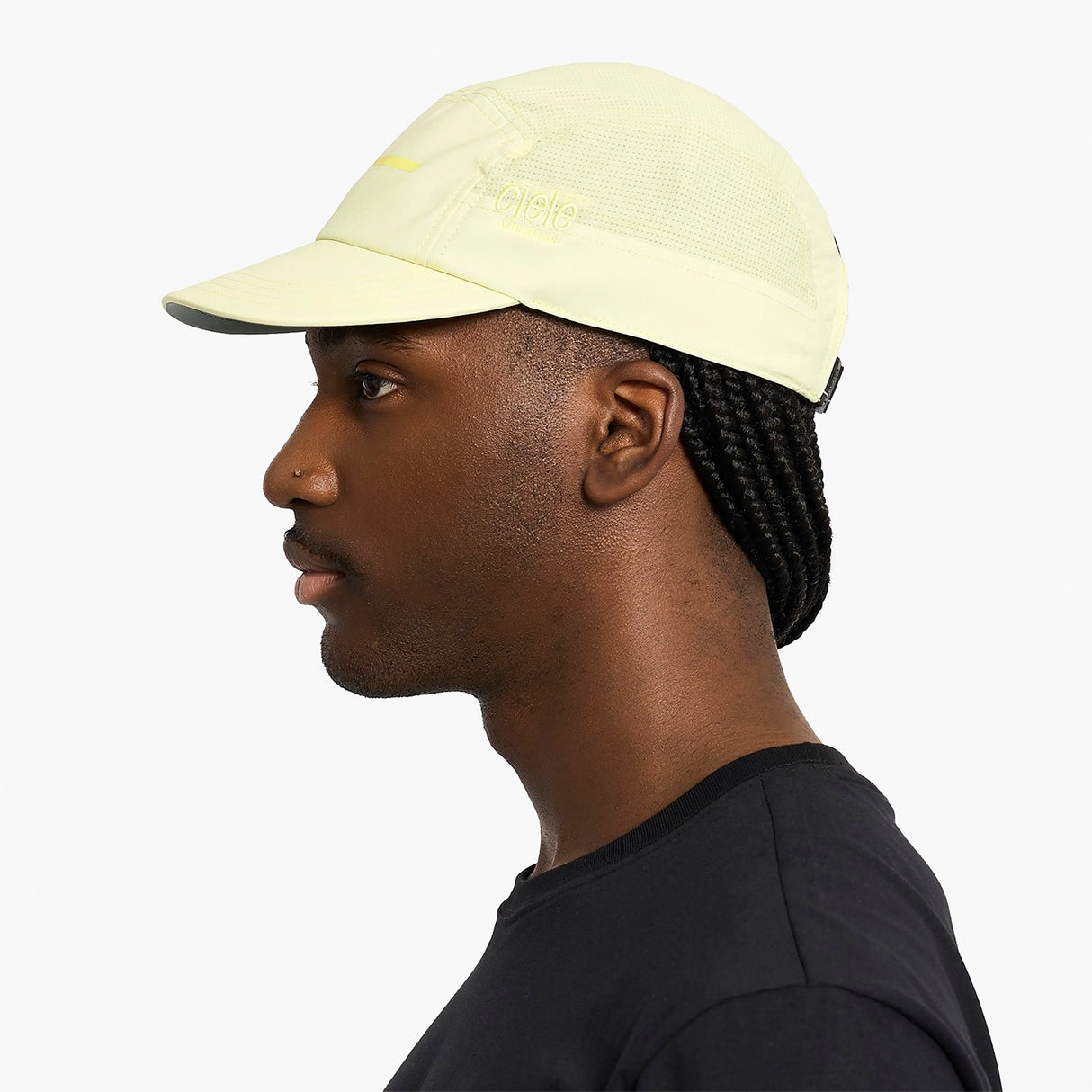 Person wearing a ciele athletics GOCap Comp - Bars Glade light yellow running cap on a white background