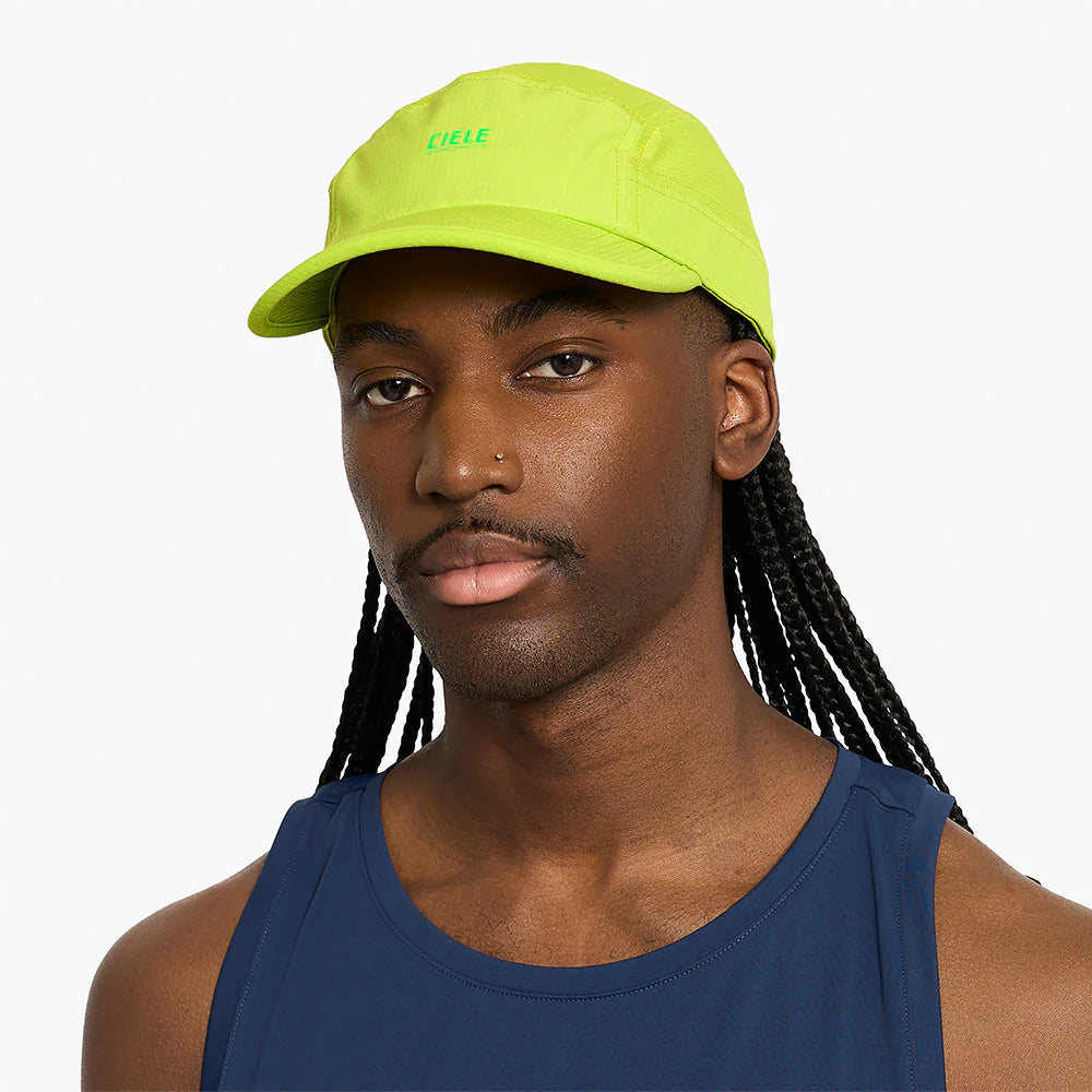 Person wearing a ciele athletics GOCap SC Field - Capital RC running hat in Lime Green with a brand logo on a white background