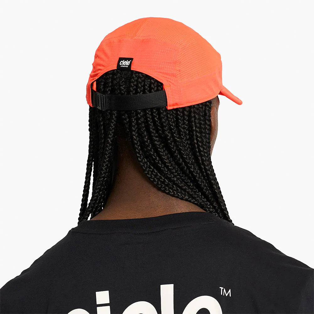 Person wearing an orange GOCap SC Field - Capital RC running hat in Infrared and black t-shirt with a brand logo on a white background