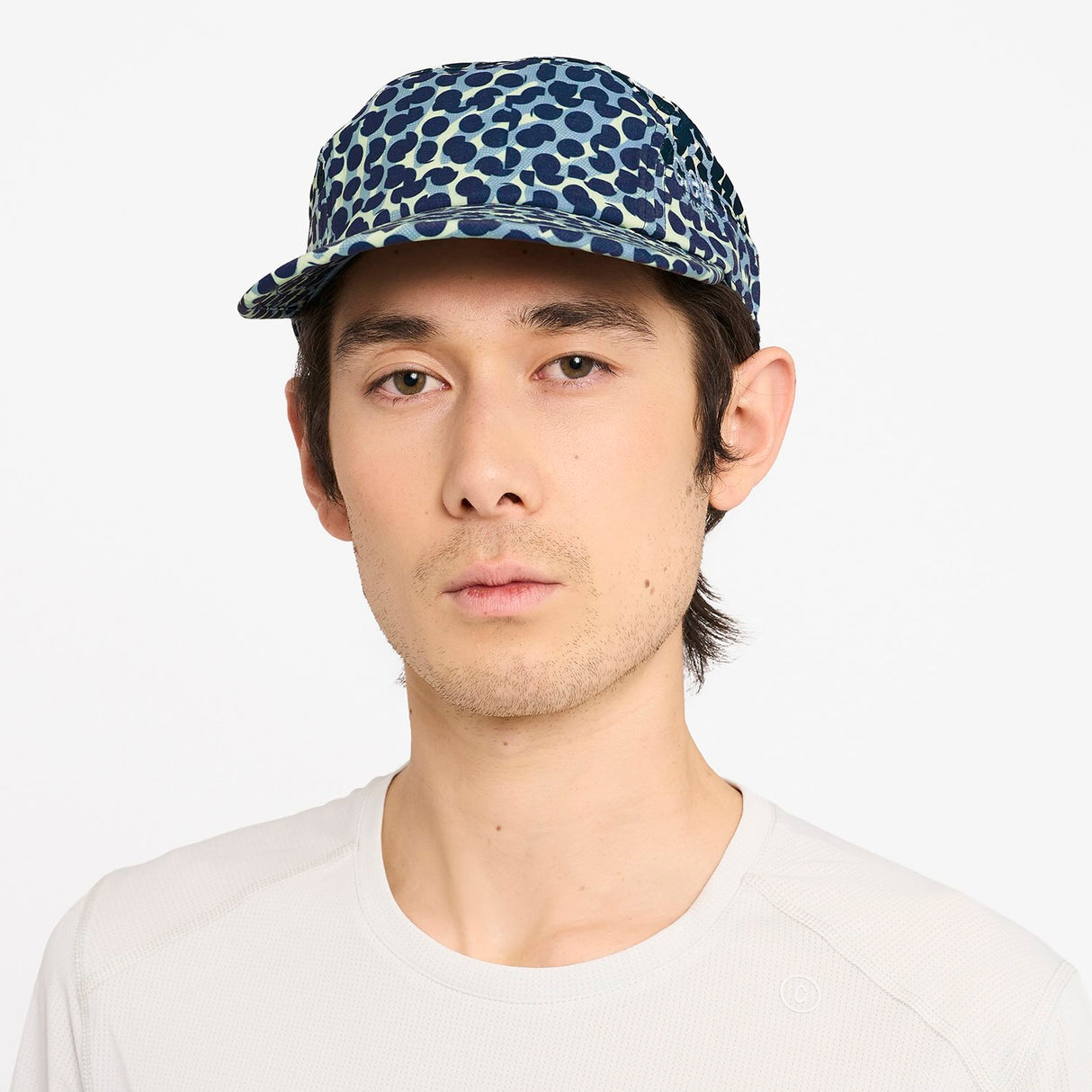 Man wearing a Ciele Athetlics GOCap SC Field - All Over Dotra running hat in Deep Space against a white background