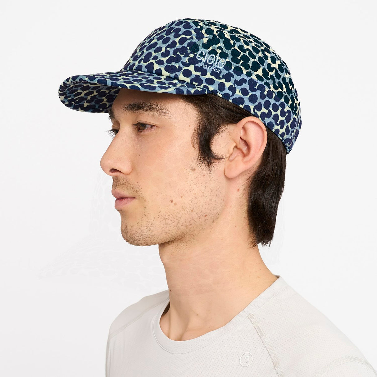 Person wearing a Ciele Athetlics GOCap SC Field - All Over Dotra running hat in Deep Space on a white background