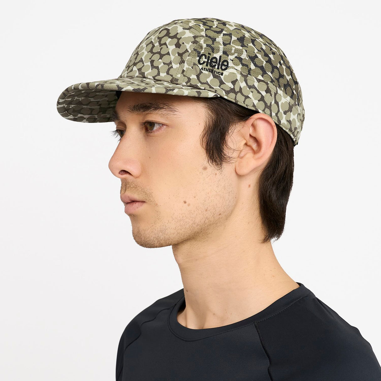Person wearing a Ciele Athetlics GOCap SC Field - All Over Dotra running hat in Canvas with 'Ciele' branding on a white background