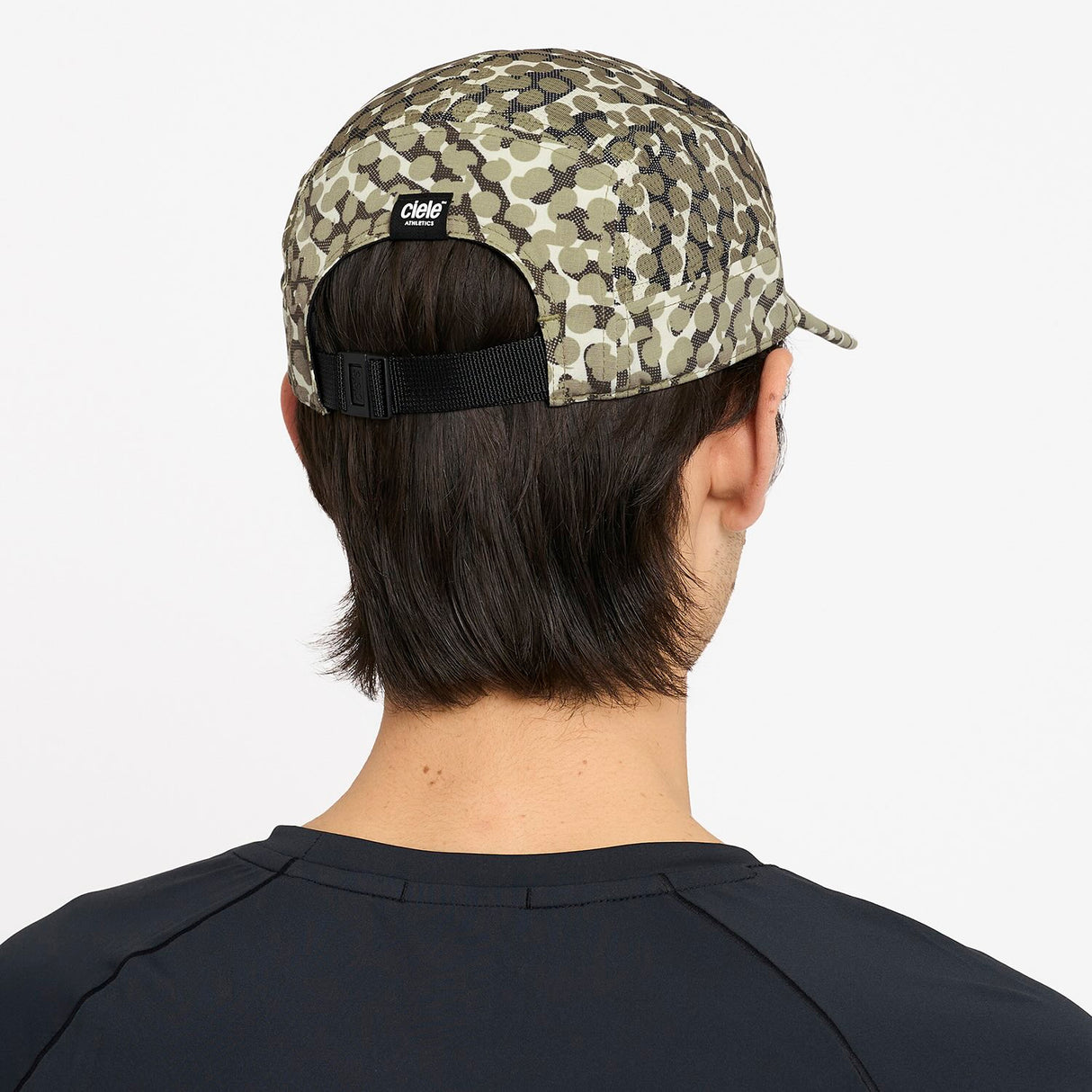 Person wearing a Ciele Athetlics GOCap SC Field - All Over Dotra running hat in Canvas on a white background