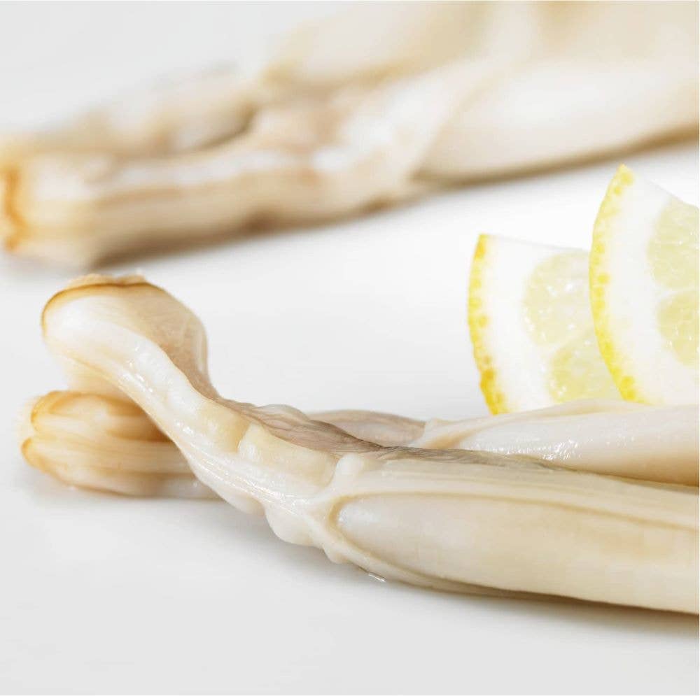 Close-up of La Narval Galician Razor Clams in Brine on a white plate with lemon wedges.