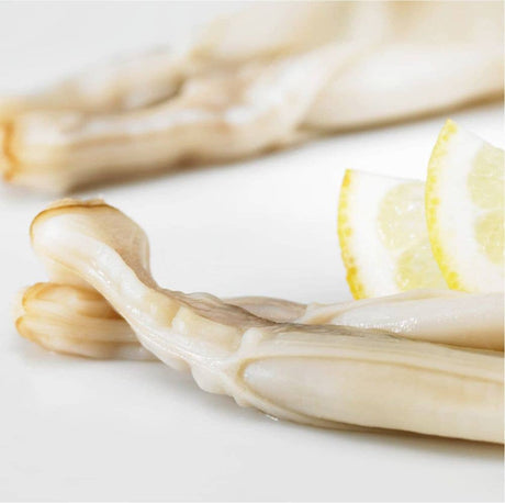 Close-up of La Narval Galician Razor Clams in Brine on a white plate with lemon wedges.
