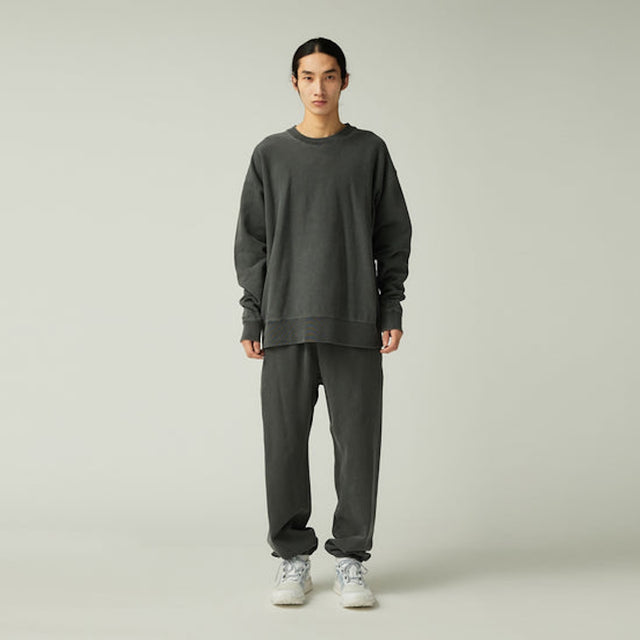 Person wearing a dark gray sweatshirt and Snow Peak Garment Dyed Pants in Charcoal with white sneakers on a light gray background