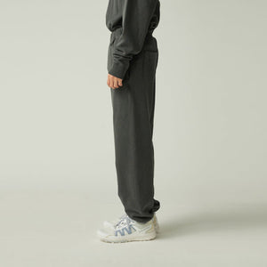 Person wearing Snow Peak Garment Dyed Pants in Charcoal with white sneakers on a light beige background