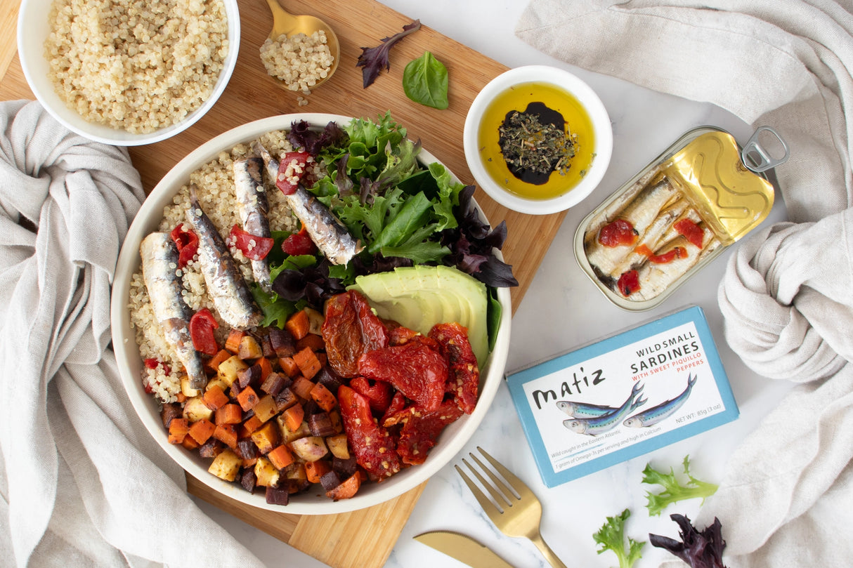 Healthy meal bowl with Matiz Wild Small Sardines with Sweet Piquillo Peppers on a wooden board.