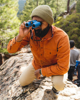Nocs Standard Issue 10x25 Waterproof Binoculars being used by a man outdoors.