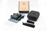 Nocs Provisions Pro Issue 8X Waterproof Binoculars in Alpine Green on a neutral background and showing the strap, carrying pouch, and case it comes with.