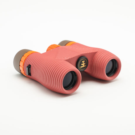 Nocs Standard Issue 10x25 Waterproof Binoculars in manzanita red on a neutral background.