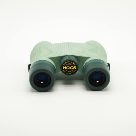 Nocs Standard Issue 8x25 Waterproof Binoculars in glacial blue on a neutral background showing the eye pieces.