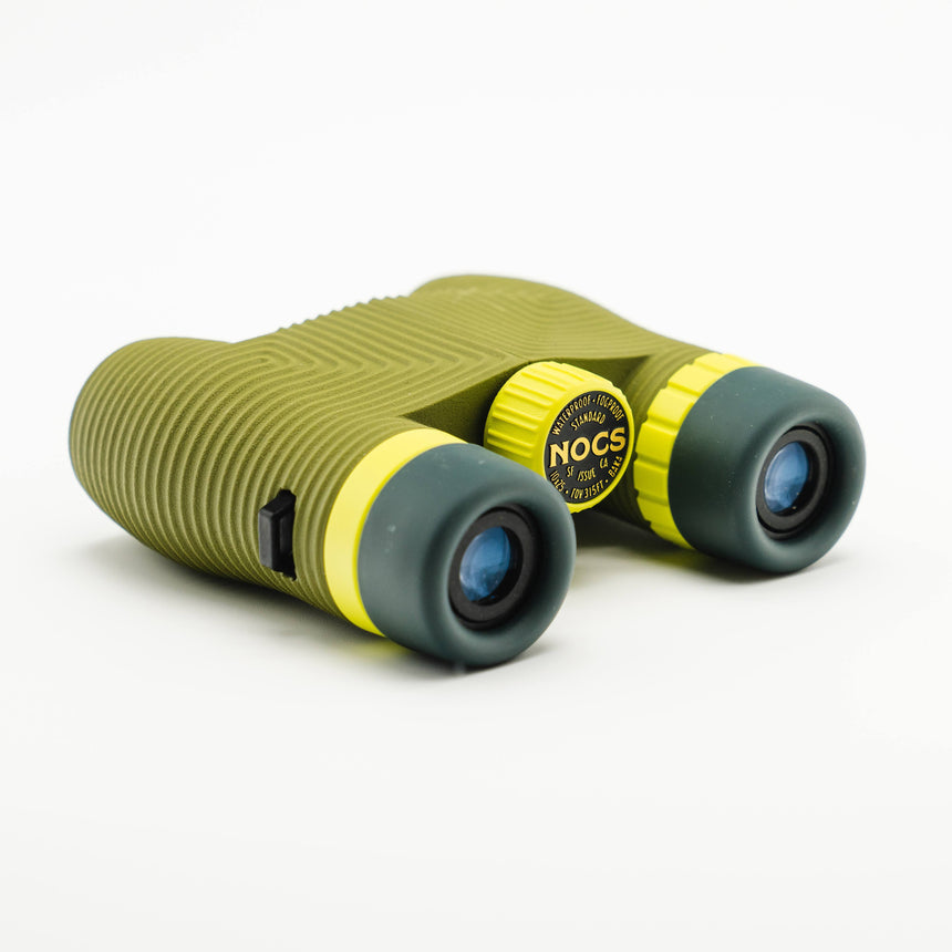 Nocs Standard Issue 10x25 Waterproof Binoculars in olive green at an angle on a neutral background.