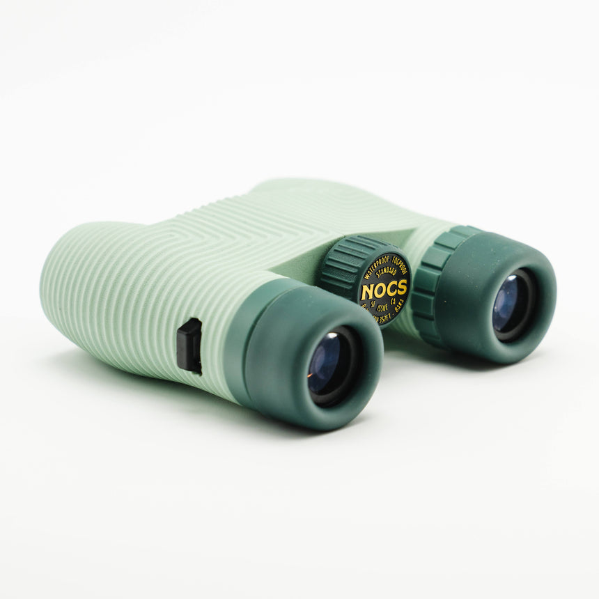 Nocs Standard Issue 8x25 Waterproof Binoculars in glacial blue on a neutral background at an angle.