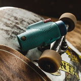 Nocs Provisions Zoom Tube 8x32 Monocular in Tahitian Blue on top of a skateboard to show its size.
