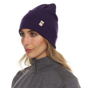 Minus33 Ridge Cuff Merino Wool Beanie in Dark Purple being worn by a woman on a neutral background.