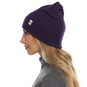 Minus33 Ridge Cuff Merino Wool Beanie in Dark Purple being worn by a woman on a neutral background.