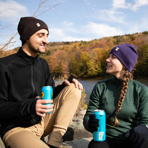 Minus33 Ridge Cuff Merino Wool Beanie in Dark Purple being worn by a woman outdoors.