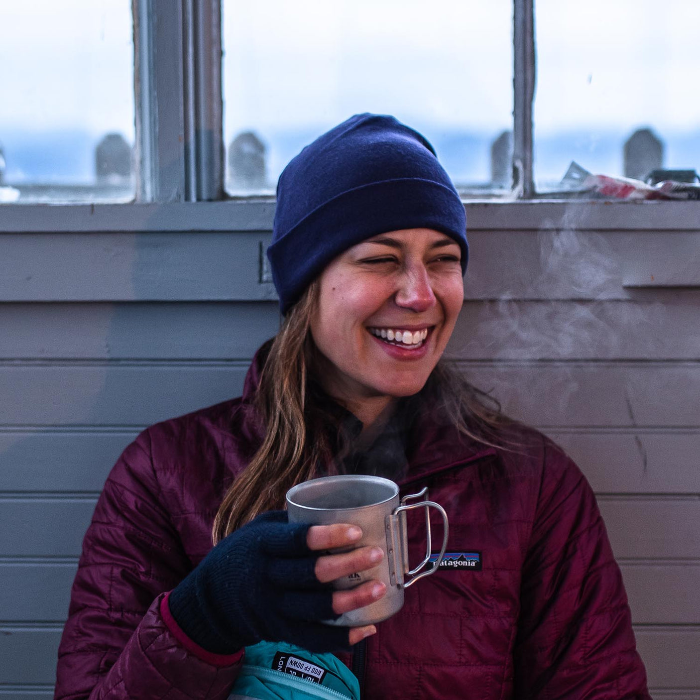 Minus33 Ridge Cuff Merino Wool Beanie in Dark Purple being worn by a woman outdoors.