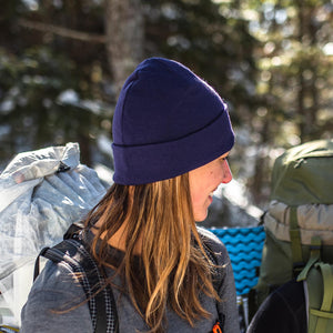 Minus33 Ridge Cuff Merino Wool Beanie in Dark Purple being worn by a woman outdoors.