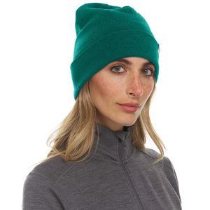 Minus33 Ridge Cuff Merino Wool Beanie in Emerald Green being worn by a woman on a neutral background.