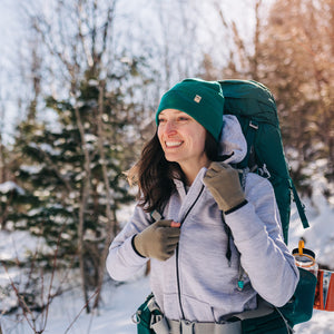 Minus33 Ridge Cuff Merino Wool Beanie in Emerald Green being worn by a woman outdoors.