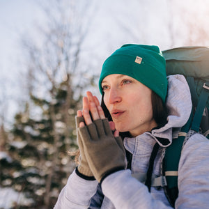 Minus33 Ridge Cuff Merino Wool Beanie in Emerald Green being worn by a woman by a woman outdoors.