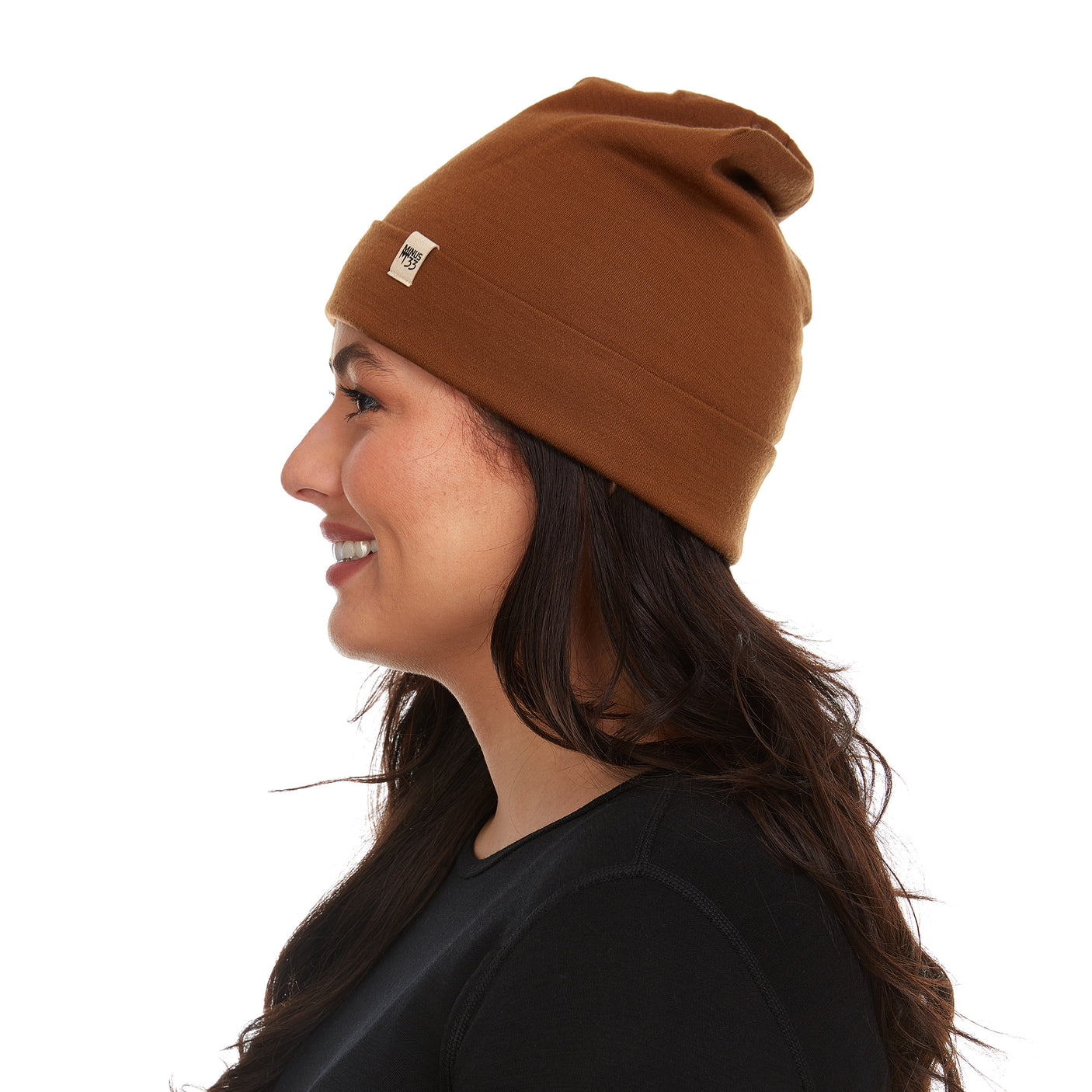 Minus33 Ridge Cuff Merino Wool Beanie in Golden Brown being worn by a woman on a neutral background.