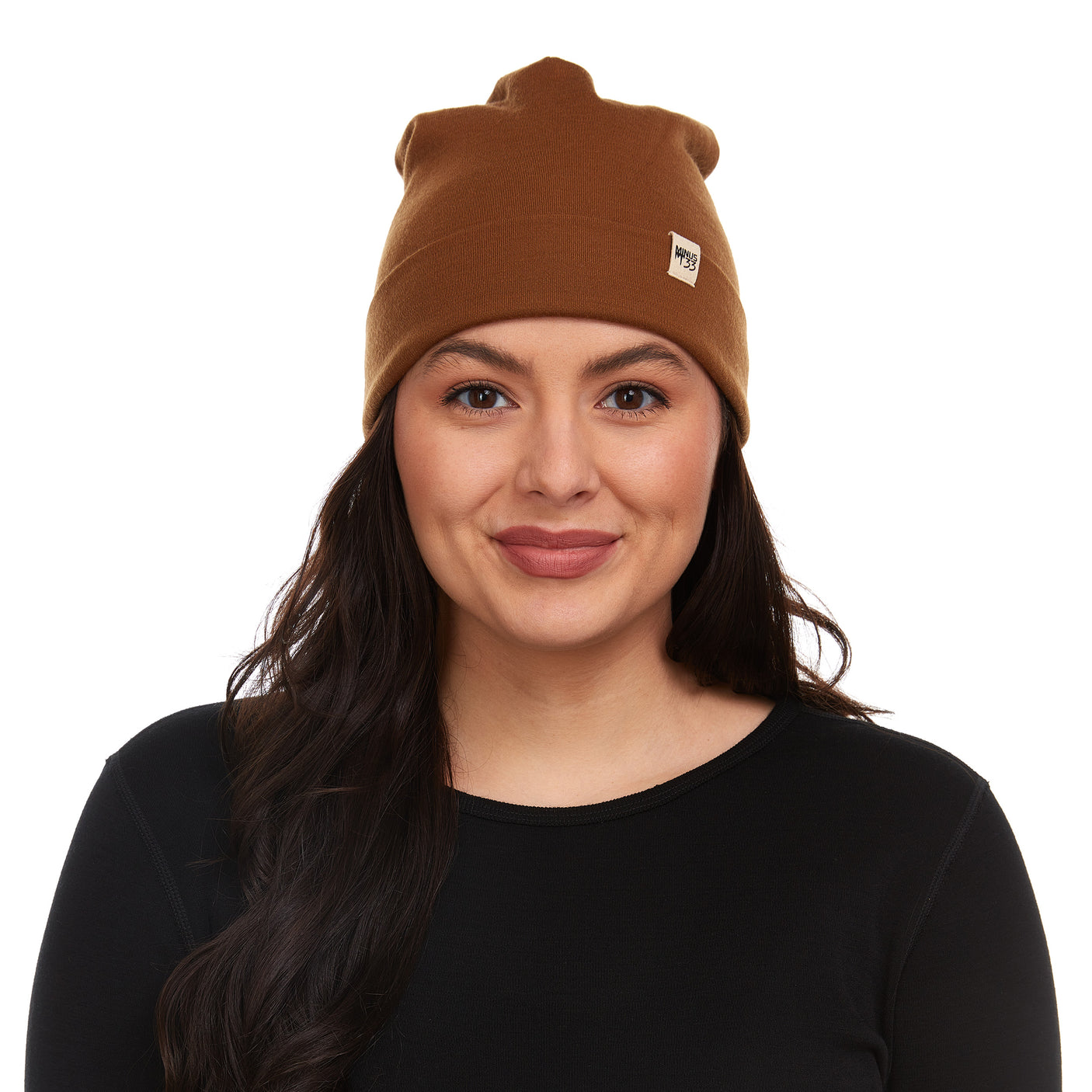 Minus33 Ridge Cuff Merino Wool Beanie in Golden Brown being worn by a woman on a neutral background.