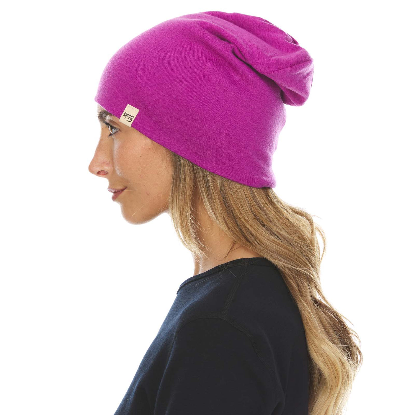 Minus33 Ridge Cuff Merino Wool Beanie in Radiant Violet being worn by a woman on a neutral background.